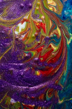 Multicolored acrylic backdrop sprinkled with purple sparkles. Contemporary creativity. Colorful avant-garde rich texture. A background made up of many shapes and materials.