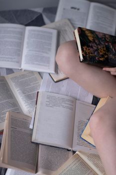 girl legs on the bed on a pile of books - vertical photo