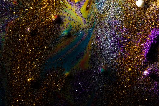 Multi-colored dark background sprinkled with purple and gold sparkles with streaks and waves. Contemporary creativity. A colorful avant-garde painting with rich texture. A background made up of many shapes and materials.