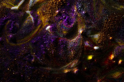 Multi-colored dark background sprinkled with purple and gold sparkles with streaks and waves. Contemporary creativity. A colorful avant-garde painting with rich texture. A background made up of many shapes and materials.