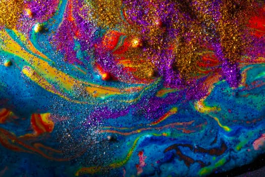 Multicolored acrylic background with curls sprinkled with purple and gold sparkles. Contemporary creativity. A colorful avant-garde painting with rich texture. A background made up of many shapes and materials.