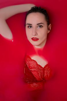 portrait of a beautiful brunette in red lingerie in red water. horror films. Photoshoot in the bathroom. copy space.