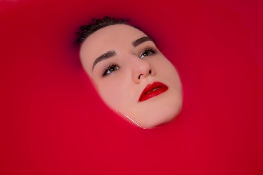 portrait of a beautiful brunette in red water. horror films. Photoshoot in the bathroom. copy space.