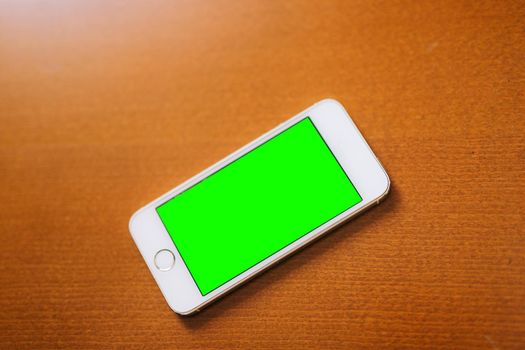 White phone on the table with a green screen.