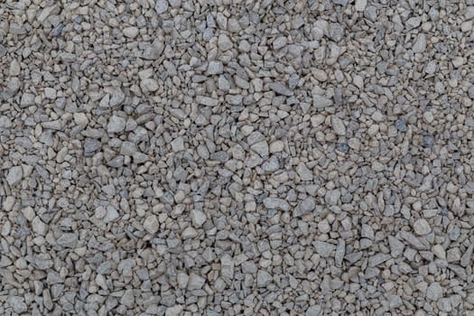 Dry white limestone ballast flat full frame background. Small gray dusty broken macadam stones texture. Viiew from above.
