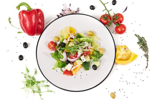 Top view of large modern plate with delicious vegetables salad on white background. Concept of beautiful composition with different colours greens and peppers. 