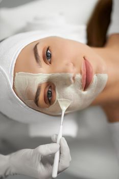 Top view portrait of young attractive woman lying on procedure for improvements and rejuvenation skin in professional beauty salon. Concept of beauty procedure with cosmetics. 