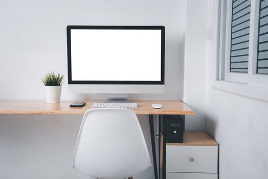 Computer monitor with white blank screen on the business desk with wireless mouse, keyboard at home office over white wall background, Photo of equipment contemporary workspace