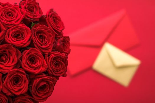 Holiday gift, flowers flatlay and happy relationship concept - Love letter and flower delivery service on Valentines Day, luxury bouquet of red roses and card envelopes on red background