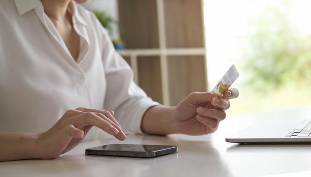 Young woman holding credit card and using smart phone for online shopping. Online payment shopping concept.