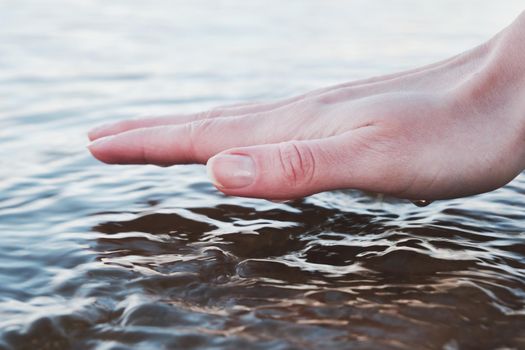 The girl touches the water surface. Outside the city