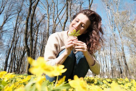 Woman enjoying smell of spring flowers. Smiling woman among spring flowers.