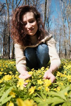 Woman enjoying smell of spring flowers. Smiling woman among spring flowers.
