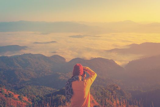 Hiker with photo camera standing on top of the mountain