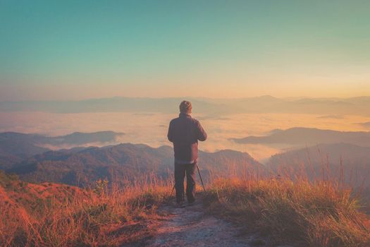 Hiker with photo camera standing on top of the mountain