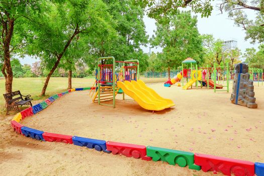 Colorful children playground activities in public park surrounded by green trees