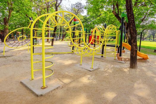 Colorful children playground activities in public park surrounded by green trees