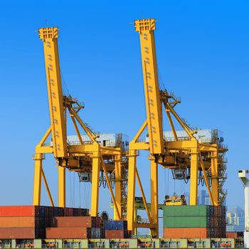 Container Cargo freight ship with working crane bridge in shipyard.