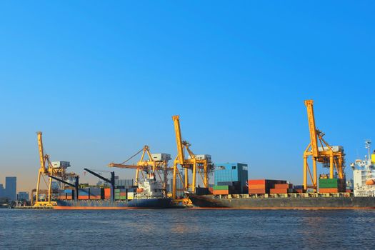 Container Cargo freight ship with working crane bridge in shipyard.