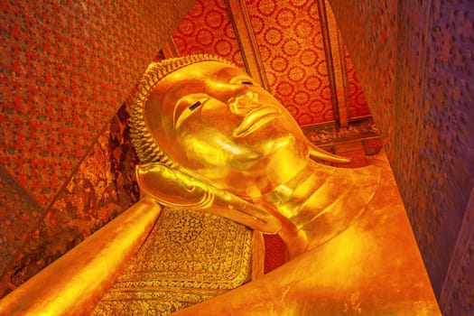 Beautiful face of Reclining Buddha,and thai art architecture in Wat Phra Chetupon Vimolmangklararm (Wat Pho) temple in Thailand.