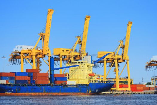 Container Cargo freight ship with working crane bridge in shipyard.