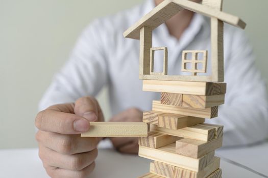 Bank worker plug in wooden blocks with model house. Copy space on wooden blocks or entering text. Concept of insurance and protect housing property.