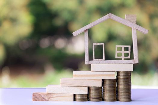 Model house on Wooden blocks stacked as stairs on stack coin money. Mortgage property insurance dream moving home and real estate concept.