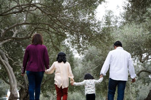 Happy family in the winter sunset light of the park. Mom, dad and happy children walk at sunset. The concept of a happy family.