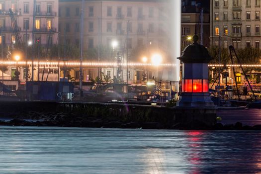 Geneva Lighthouse and water fountain at night. Geneva, Switzerland.