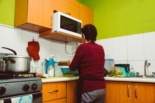 Senior woman preparing healthy home food from fresh vegetables in kitchen.