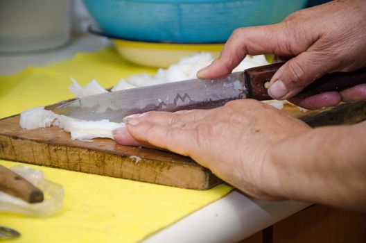 Woman's hands in the kitchen cutting a piece of meat into pieces