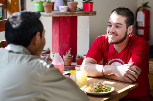 Good looking men having lunch in an outdoor restaurant, men chatting and smiling