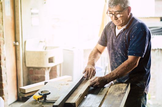 Professional carpenter cutting wooden board at his workshop