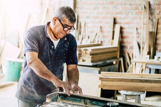 Professional carpenter cutting wooden board at his workshop