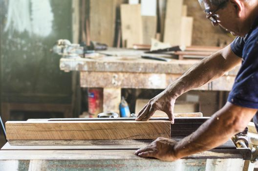 Professional carpenter cutting wooden board at his workshop