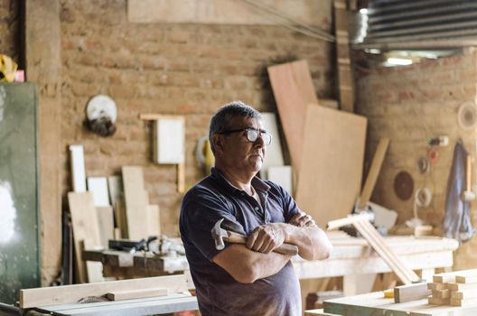 Portrait of senior carpenter. Standing with the background of your carpentry behind