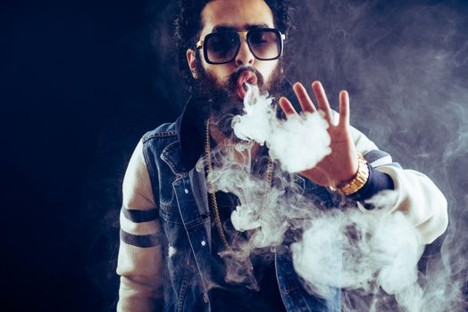 Smoking vape. vaping man holding a mod. Vape Rings. A man launches a ring of smoke. Tricks with smoke.