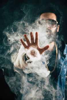 Smoking vape. vaping man holding a mod. Vape Rings. A man launches a ring of smoke. Tricks with smoke.