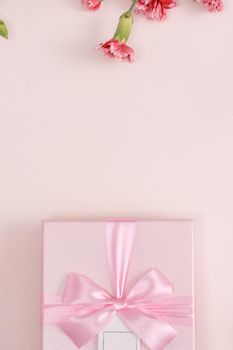 Mother's day background concept. Top view design of holiday greeting gift with carnation bouquet on bright pink table background