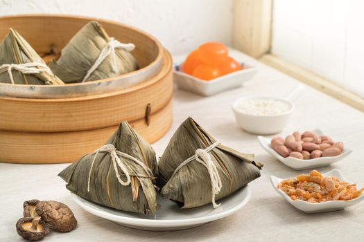 Zongzi. Rice dumpling for Chinese traditional Dragon Boat Festival (Duanwu Festival) on bright wooden table background with window.