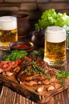  Fried pork steak on a wooden board to serve with vegetables and a mug of beer.