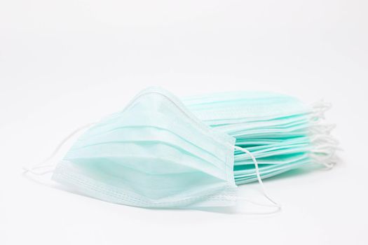A stack of medical face masks on a white background. Article about the second wave of coronavirus. Protection of the respiratory system. Pneumonia and coronavirus. Pandemic. Copy space