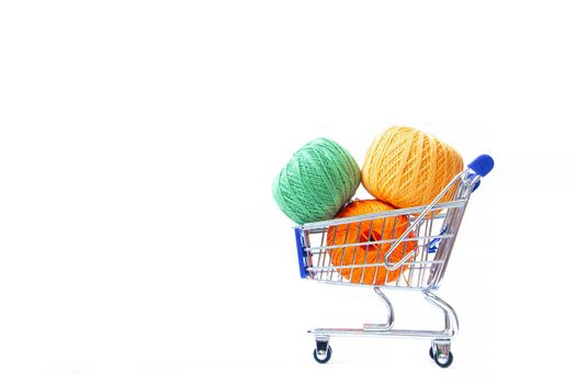 Trolley with yarn for knitting. Yarn for crocheting. Design of the embroidery section. Needlework. Hobbies and recreation. Colored threads on a white background. Isolated objects. Copy space