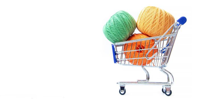 Trolley with yarn for knitting. Yarn for crocheting. Design of the embroidery section. Needlework. Hobbies and recreation. Colored threads on a white background. Isolated objects. Copy space