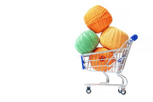 Trolley with yarn for knitting. Yarn for crocheting. Design of the embroidery section. Needlework. Hobbies and recreation. Colored threads on a white background. Isolated objects. Copy space