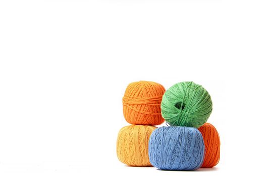 Colored balls of crochet thread on a white background . Copy space. The tangles are arranged in a column. Article about crocheting. Selection of threads for crocheting. Features of choosing a material for knitting. Made by the hands. Leisure for pensioners.