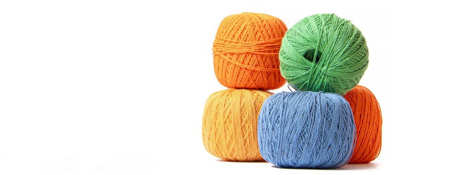 Colored balls of crochet thread on a white background . Copy space. The tangles are arranged in a column. Article about crocheting. Selection of threads for crocheting. Features of choosing a material for knitting. Made by the hands. Leisure for pensioners.