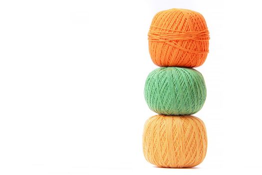 Colored balls of crochet thread on a white background . Copy space. The tangles are arranged in a column. Article about crocheting. Selection of threads for crocheting. Features of choosing a material for knitting. Made by the hands. Leisure for pensioners.
