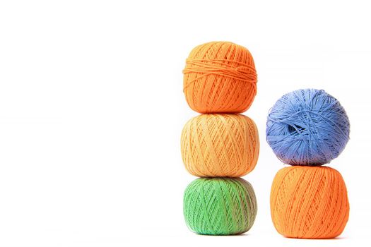 Colored balls of crochet thread on a white background . Copy space. The tangles are arranged in a column. Article about crocheting. Selection of threads for crocheting. Features of choosing a material for knitting. Made by the hands. Leisure for pensioners.
