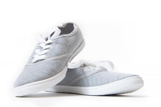 Sneakers are gray isolated on a white background . Women's sneakers . Unisex shoes. Article about the harm of shoes with rubber soles. Choice of shoes for summer.